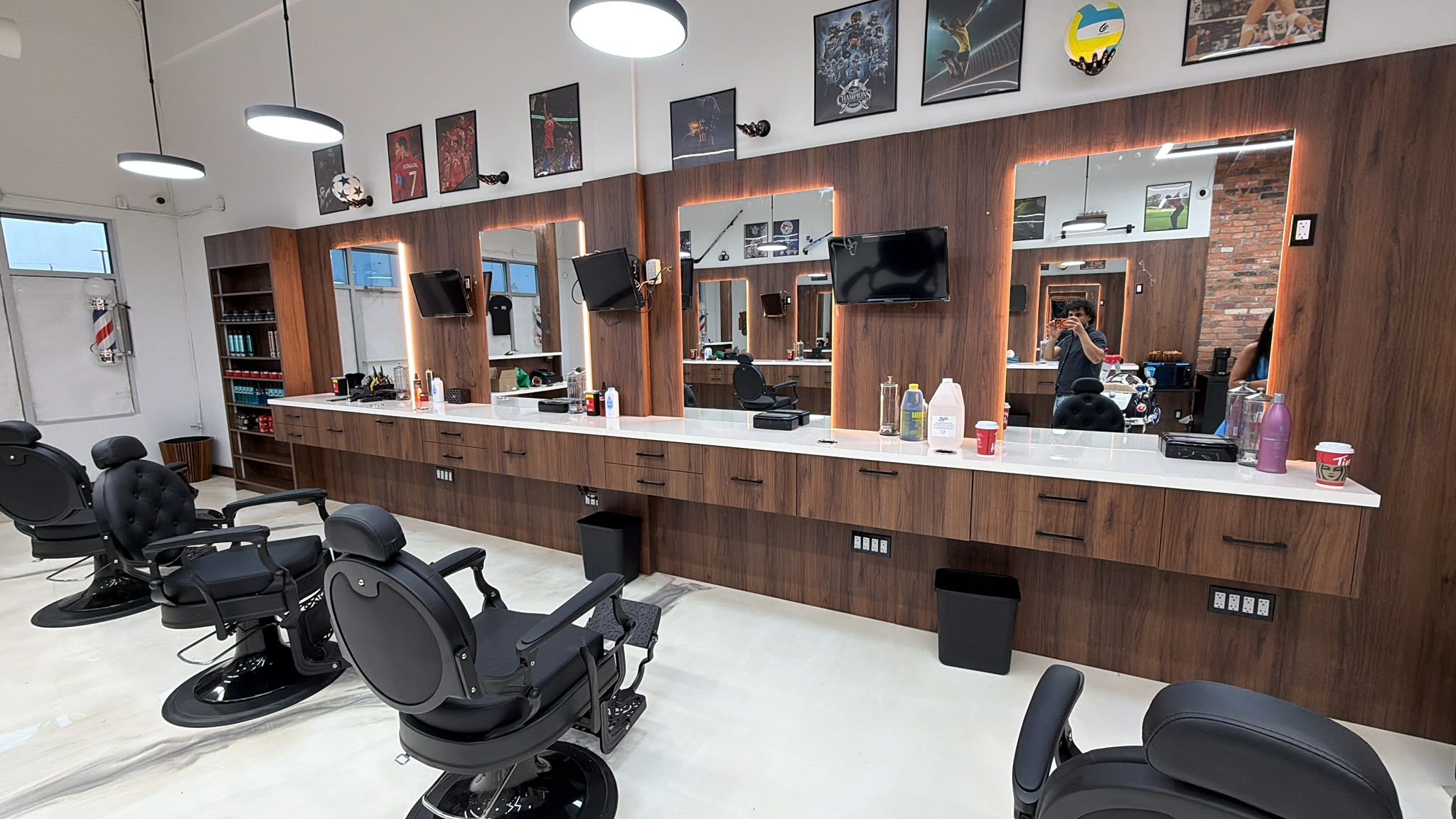 Inside New Legend Barbershop in Hamilton, ON: black leather barber chairs facing a row of backlit mirrors on walnut panelling